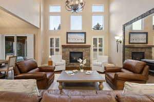 Living area with a fireplace, hanging lights, a high ceiling, and wood finished floors