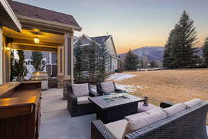 Patio terrace at dusk with an outdoor fire pit, a patio, an outdoor kitchen with living area, and a mountain view