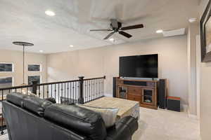 Living area with light carpet, a ceiling fan, a textured ceiling, and recessed lighting