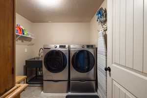 Laundry area featuring a textured ceiling, unfinished concrete flooring, and separate washer and dryer
