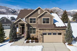 Craftsman-style home featuring board and batten siding, a mountain view, stone siding, and driveway