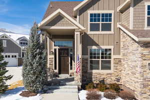 Entrance to property with board and batten siding, stone siding, and a shingled roof