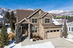 Craftsman-style house with a mountain view, stone siding, board and batten siding, a shingled roof, and driveway