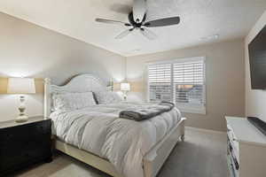 Bedroom with carpet flooring, a textured ceiling, and a ceiling fan