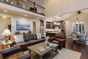 Living area featuring dark wood finished floors, a chandelier, and a high ceiling