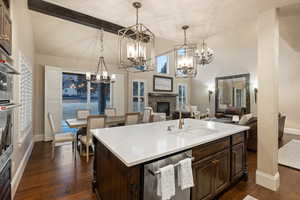 Kitchen with dark wood finish cabinets, a fireplace, stainless steel appliances, dark wood-style flooring, and vaulted ceiling