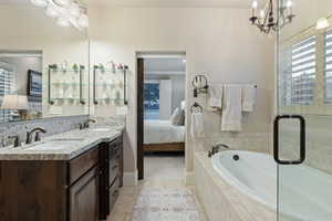 Bathroom with ensuite bath, suspended lighting, a bath, double vanity, and light tile patterned floors