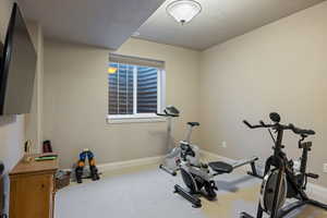 Exercise area with light carpet and a textured ceiling