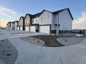 View of side of property with a garage, a residential view, board and batten siding, driveway, and brick siding