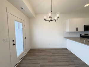 Unfurnished dining area featuring dark wood-style flooring and hanging lights