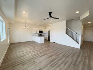 Unfurnished living room featuring suspended lighting, dark wood-style flooring, and ceiling fan