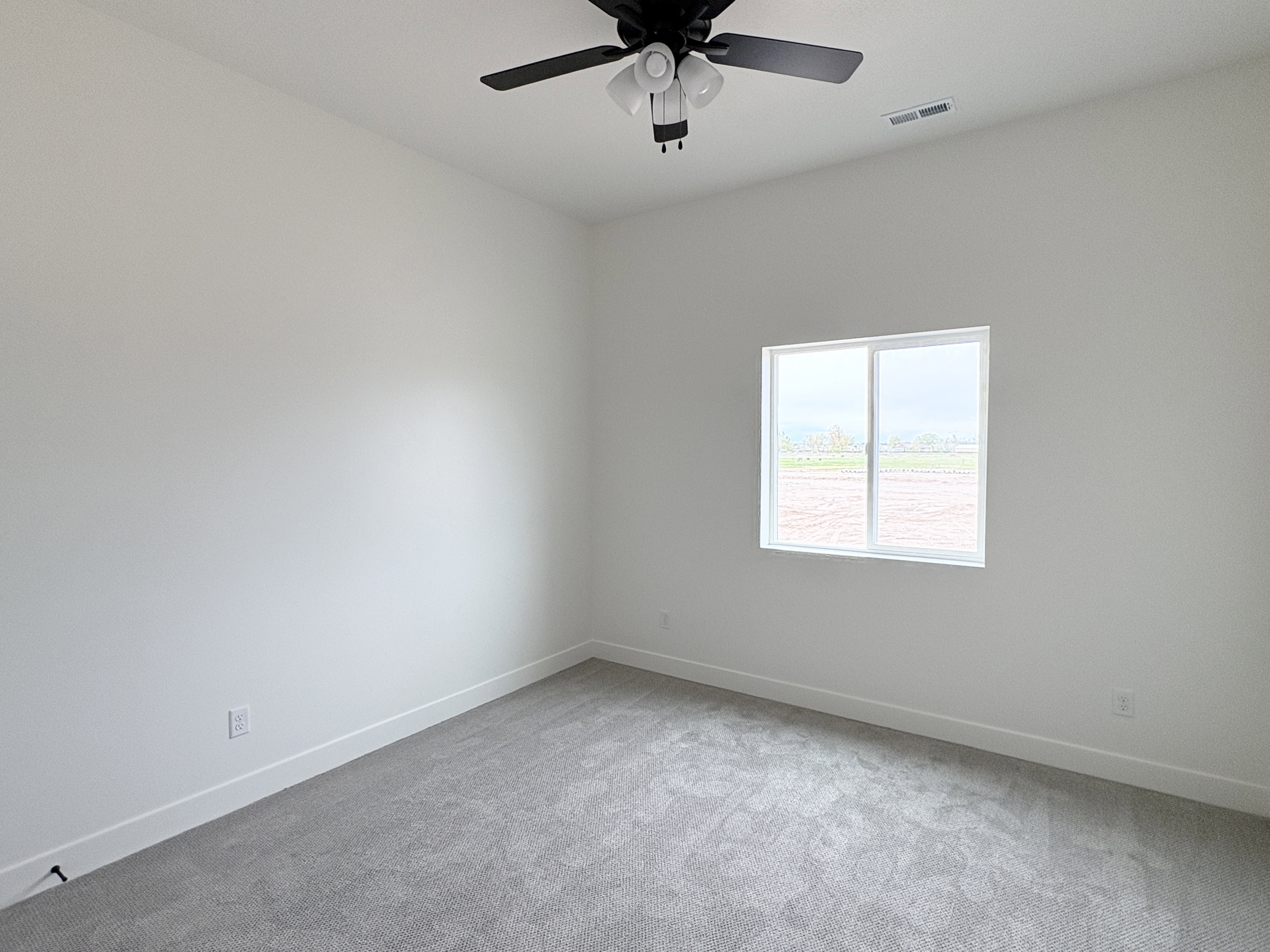Empty room with light carpet and a ceiling fan