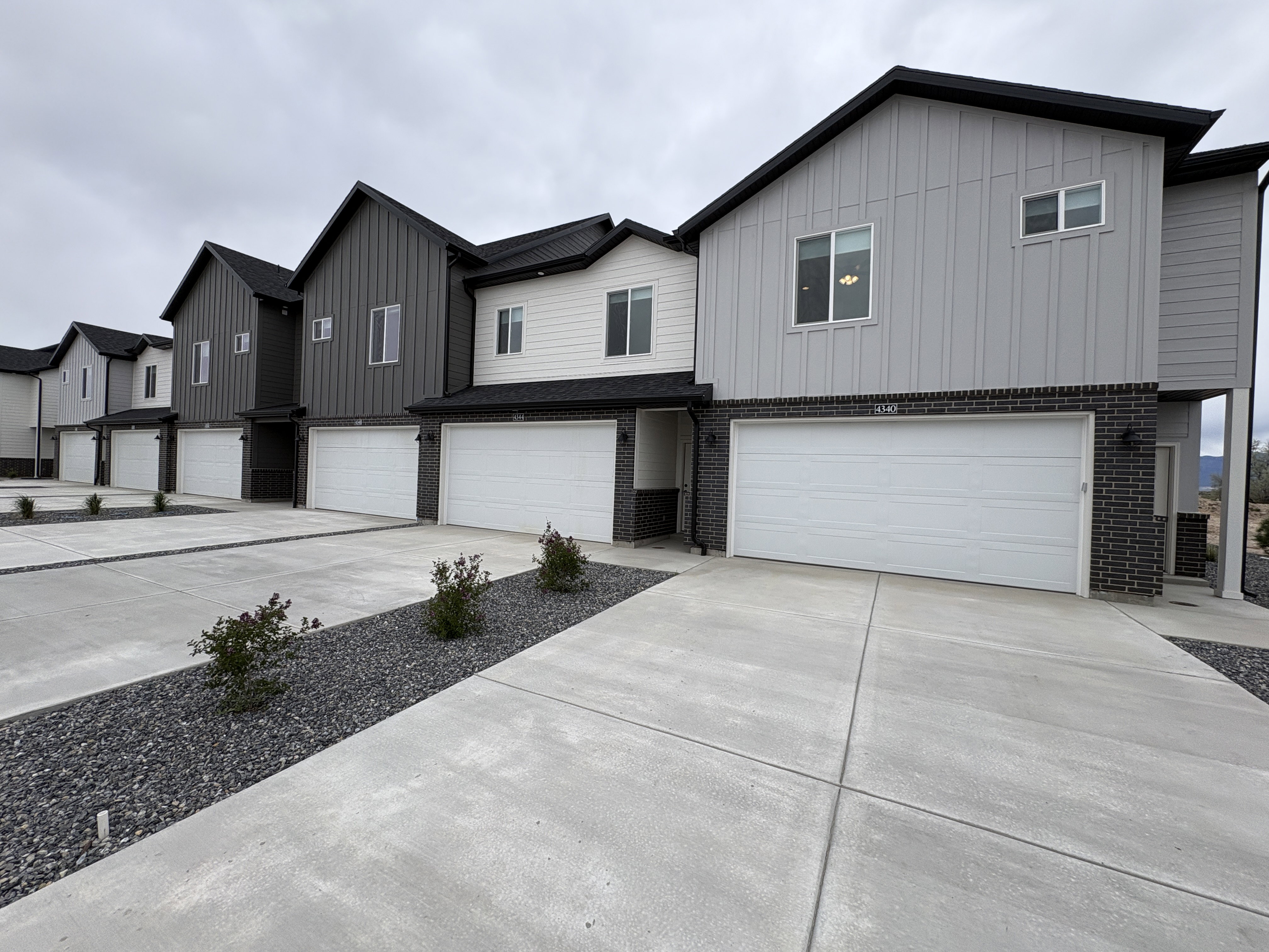 View of front of house with board and batten siding, a garage, brick siding, and concrete driveway