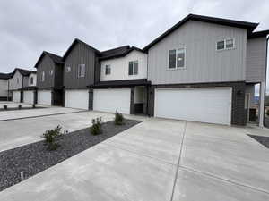 View of front of house with board and batten siding, a garage, brick siding, and concrete driveway