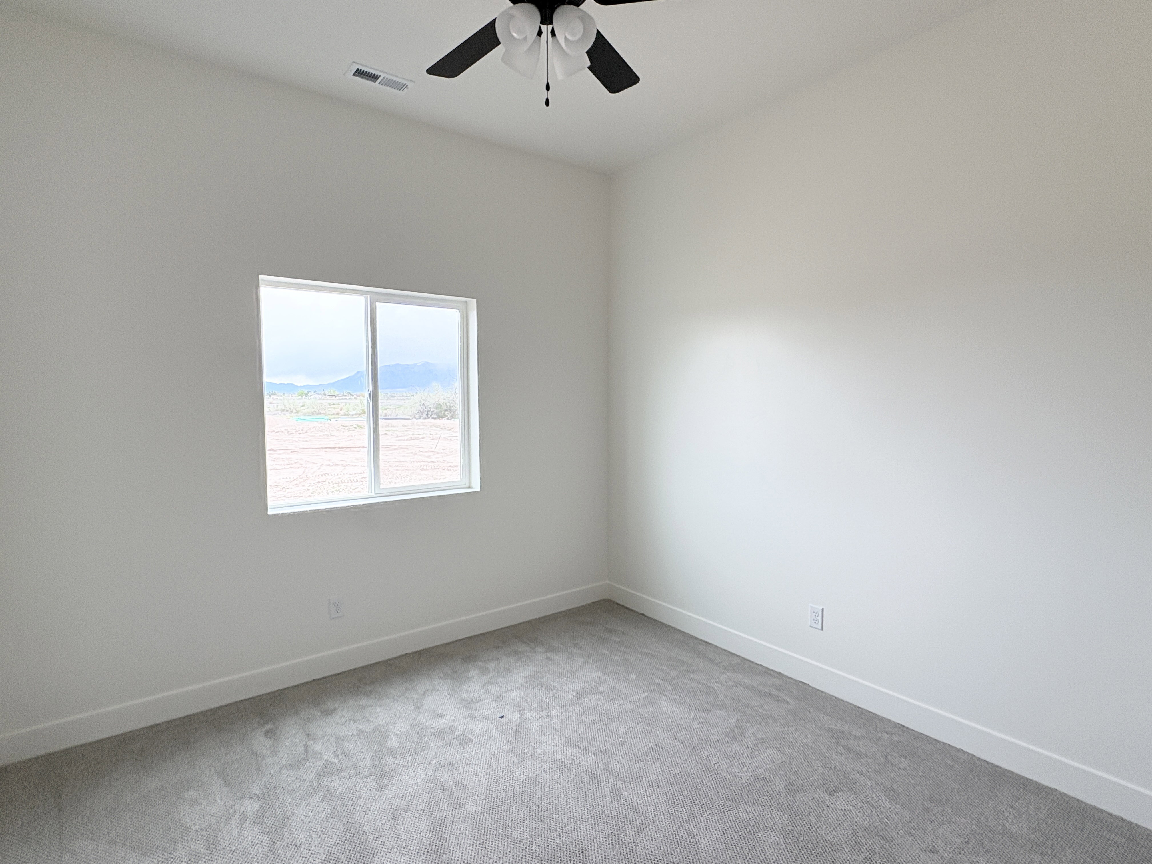 Empty room featuring light carpet and a ceiling fan