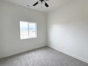 Empty room featuring light carpet and a ceiling fan