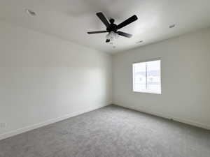 Carpeted spare room with baseboards and a ceiling fan