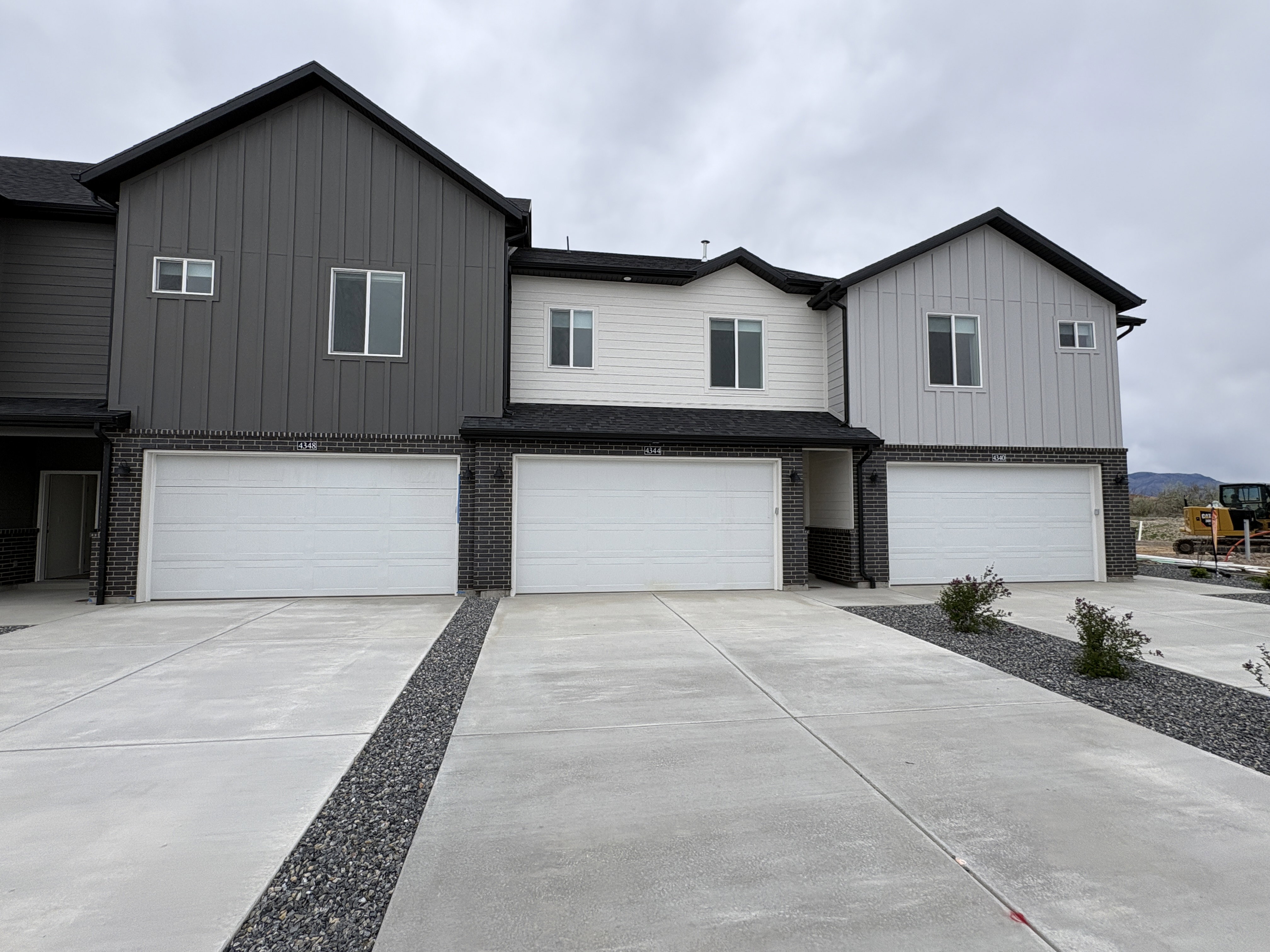 View of front of house featuring a garage, board and batten siding, concrete driveway, and brick siding