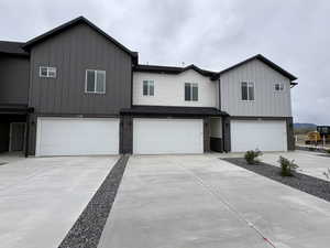 View of front of house featuring a garage, board and batten siding, concrete driveway, and brick siding