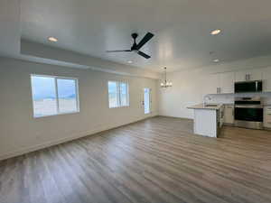 Kitchen featuring stainless steel appliances, hanging lights, open floor plan, white cabinetry, and ceiling fan