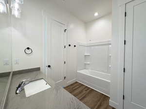 Bathroom with vanity, dark wood finished floors,  shower combination, and recessed lighting