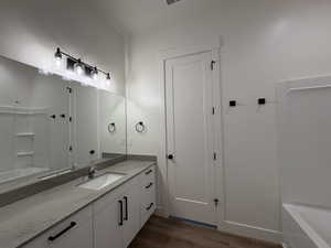 Full bathroom featuring vanity, washtub / shower combination, and dark wood finished floors