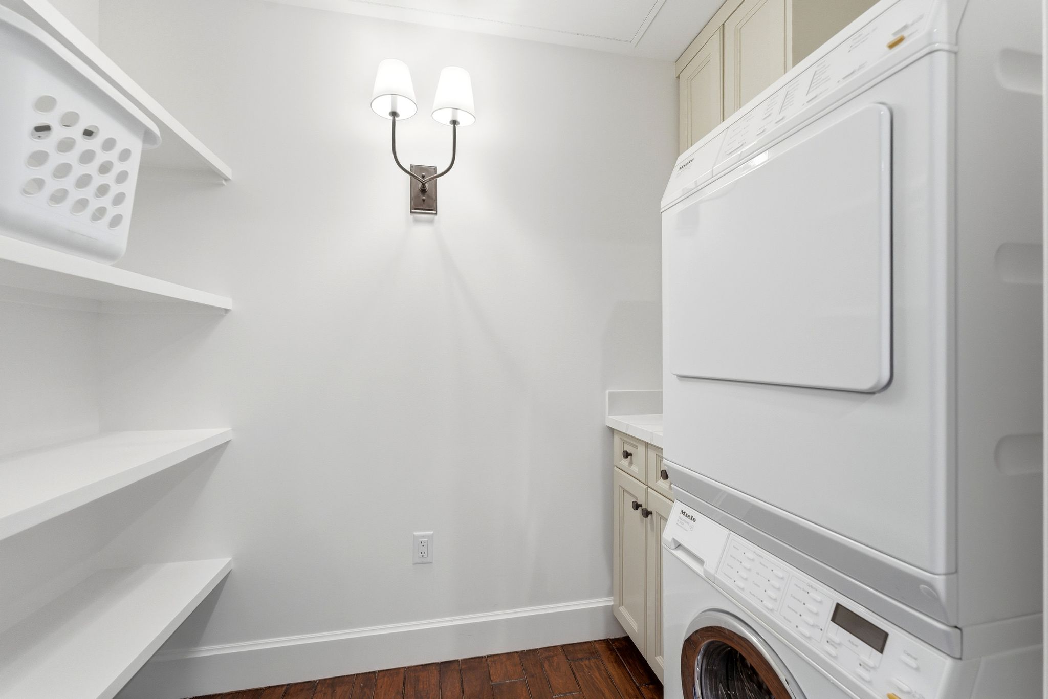 Laundry area with stacked washer / dryer, dark wood-type flooring, and cabinet space