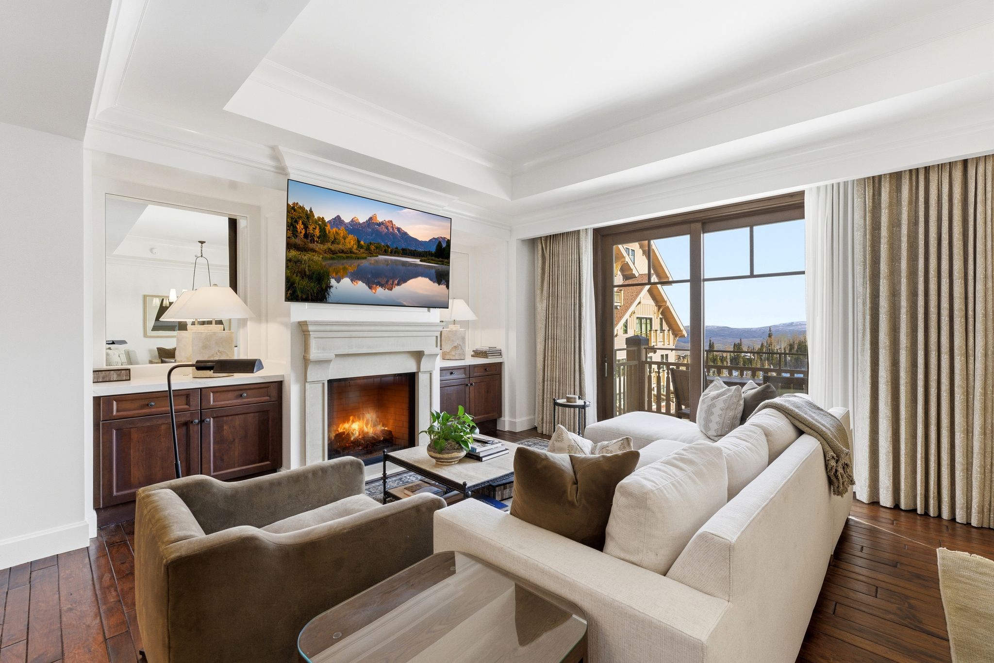 Living area with dark wood-style flooring, a warm lit fireplace, and a raised ceiling