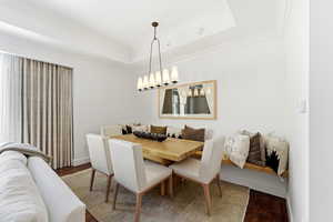 Dining space featuring wood finished floors, ornamental molding, a raised ceiling, and breakfast area