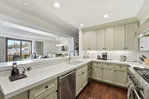 Kitchen featuring light stone counters, stainless steel appliances, dark wood-style floors, ornamental molding, and hanging light fixtures