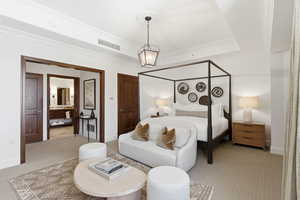 Bedroom with crown molding, carpet floors, a tray ceiling, connected bathroom, and suspended lighting
