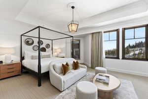 Carpeted bedroom featuring a tray ceiling and ornamental molding