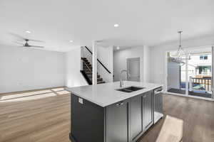 Kitchen with light wood-style floors, ceiling fan, a center island with sink, and open floor plan