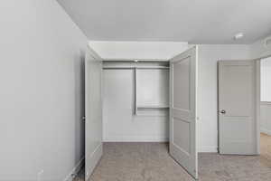 Unfurnished bedroom with light colored carpet, a textured ceiling, and a closet