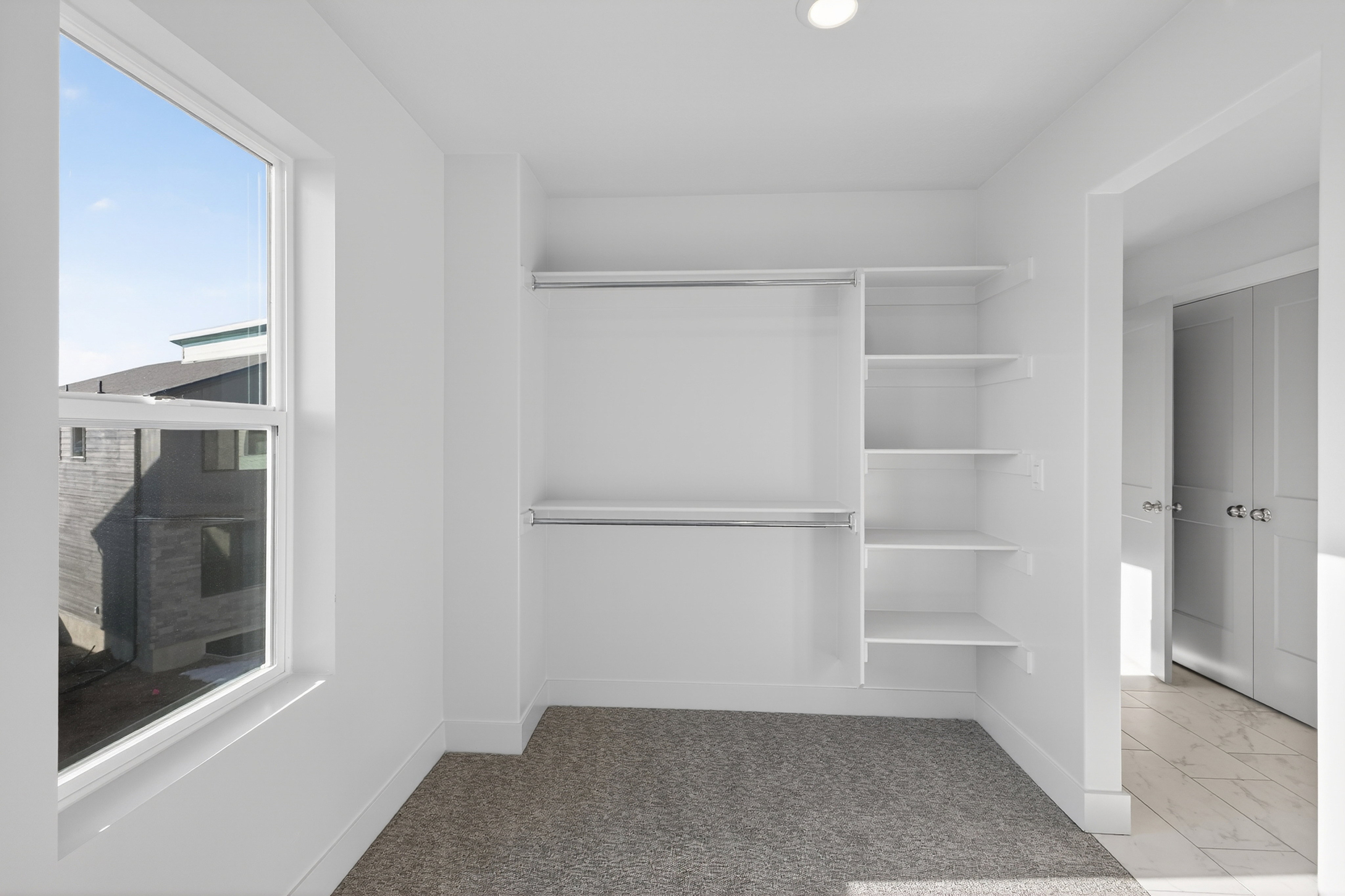 White-painted room featuring a built-in closet system with hanging rods and shelving