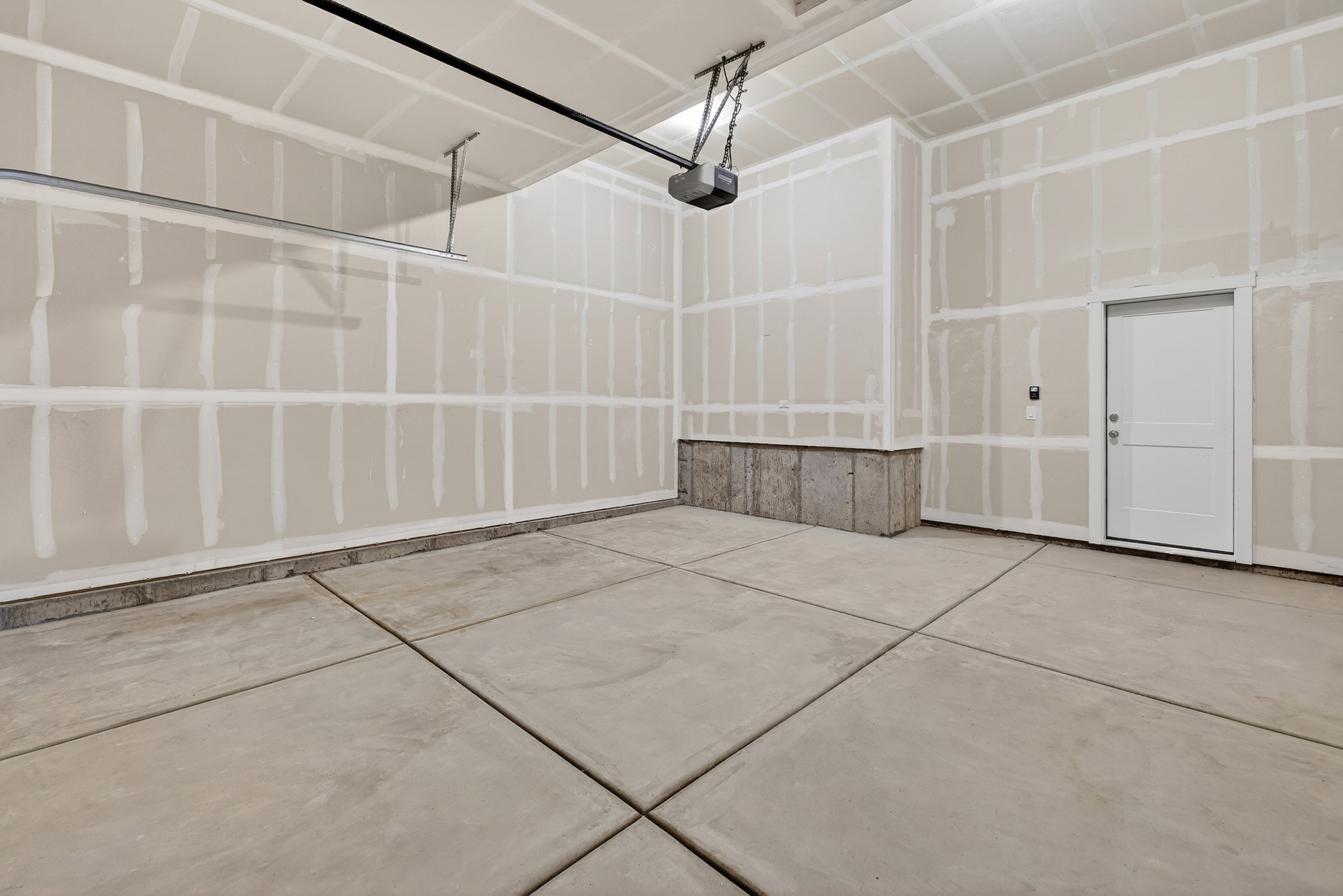 Spacious garage featuring a concrete slab floor, finished drywall walls, overhead lighting, and an internal access door