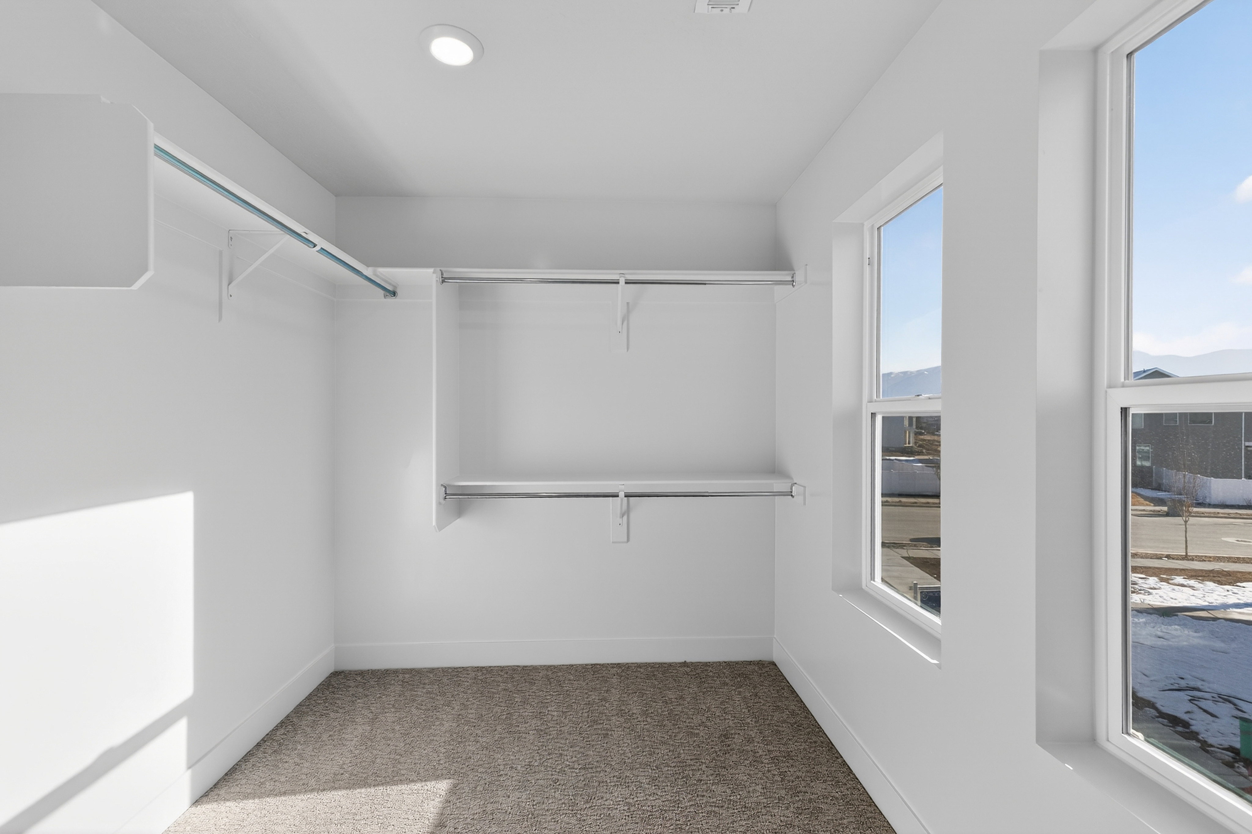 Closet space featuring neutral carpet, recessed lighting, and multiple windows