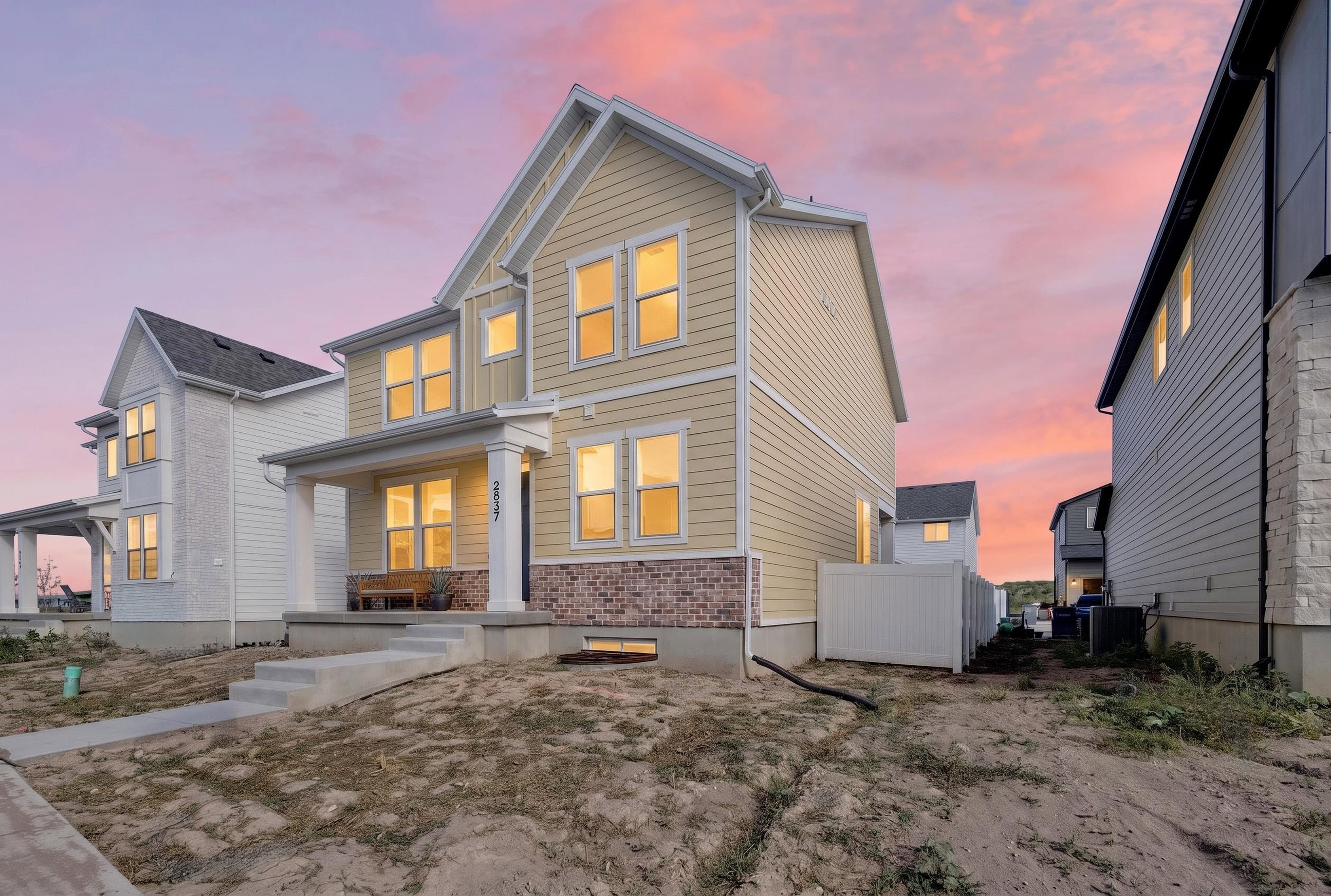 Two-story residence featuring light-colored horizontal siding and a red brick accent facade