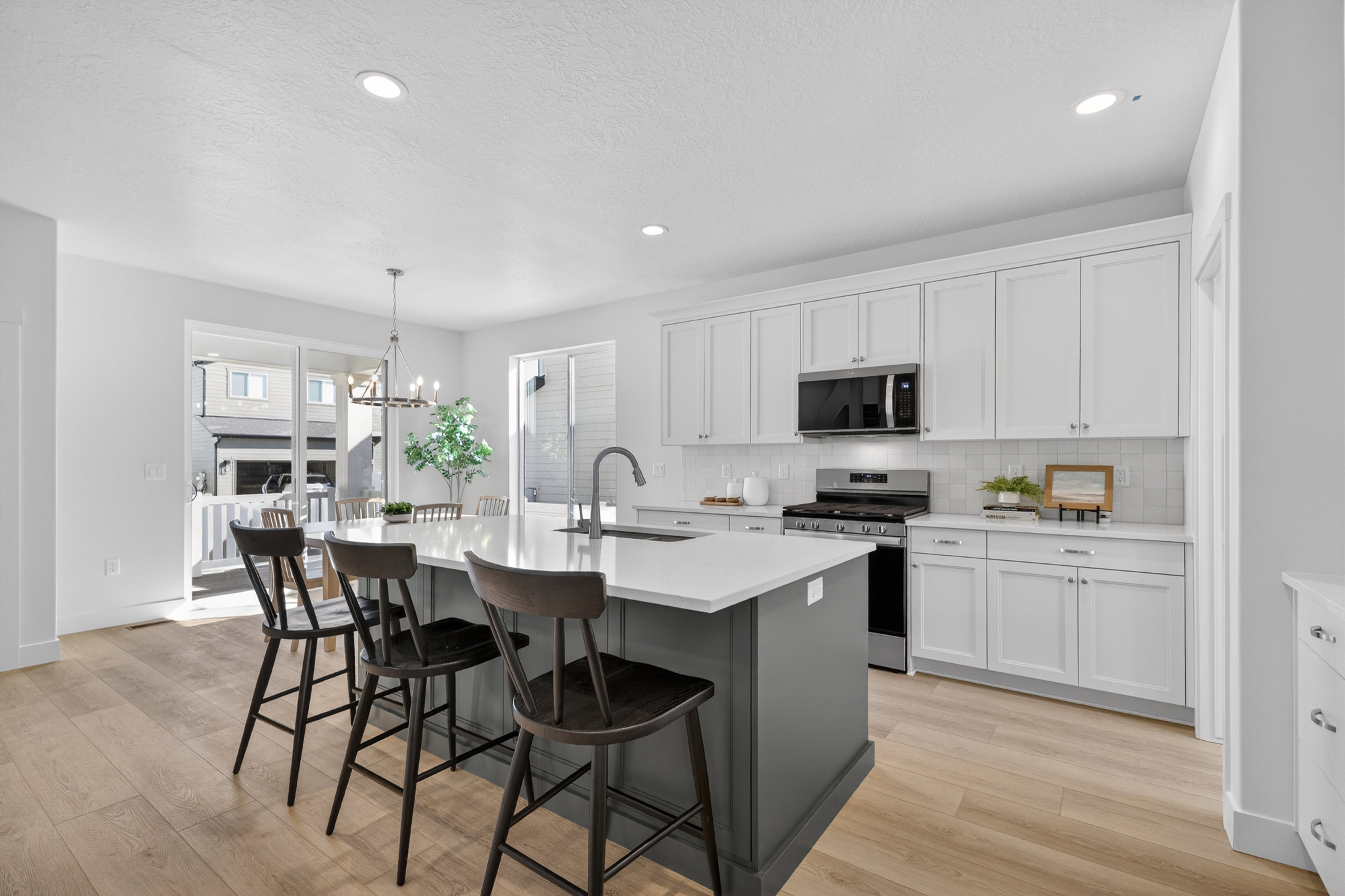 Contemporary kitchen featuring light wood-finish flooring, white cabinetry, and a grey kitchen island with an integrated sink