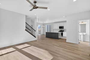 Unfurnished living room featuring ceiling fan, suspended lighting, and light wood finished floors