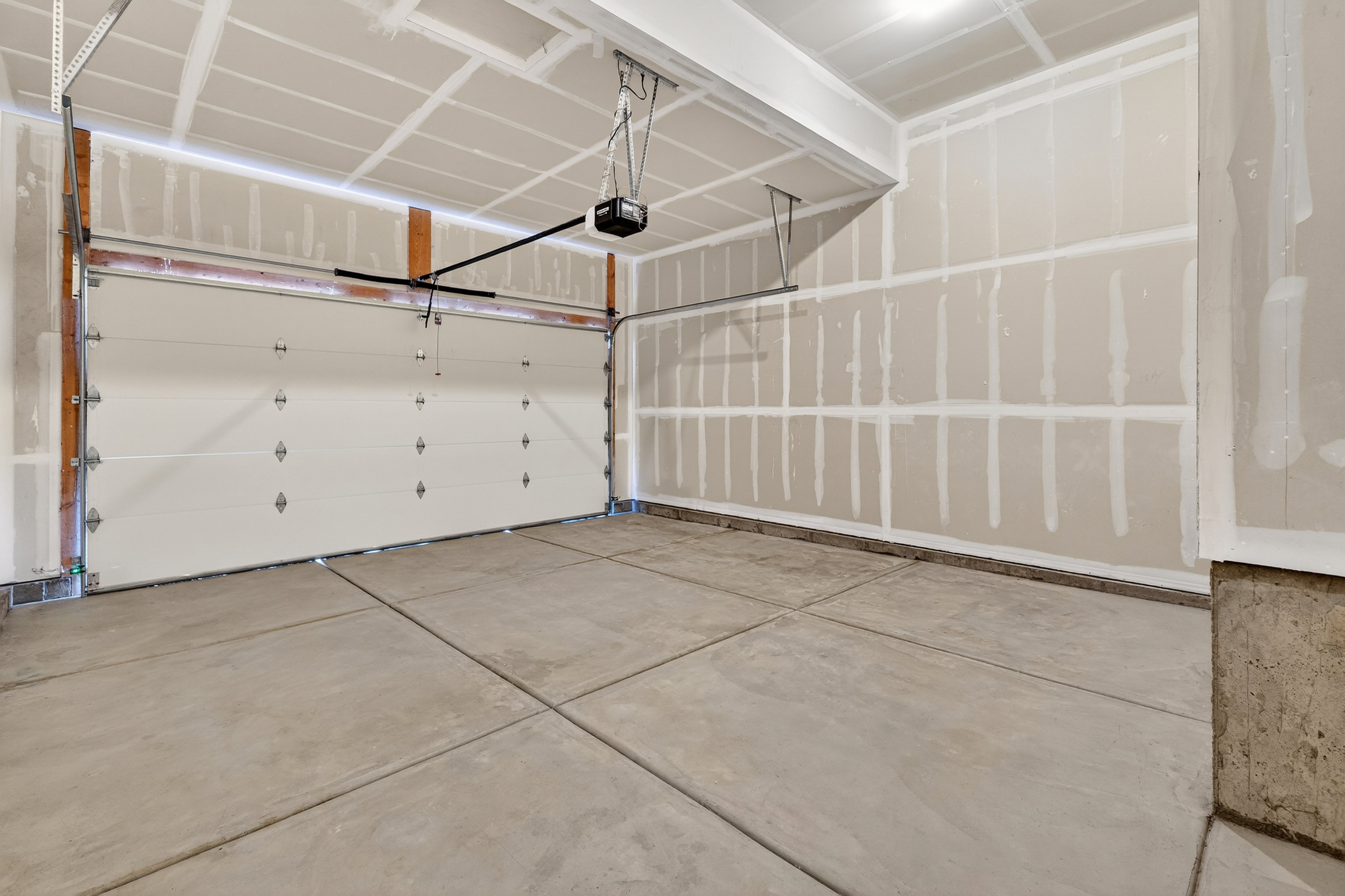 Spacious garage featuring a concrete slab floor, unfinished drywall walls, and an automatic overhead door