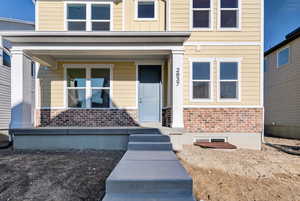 View of exterior entry featuring brick siding and a porch