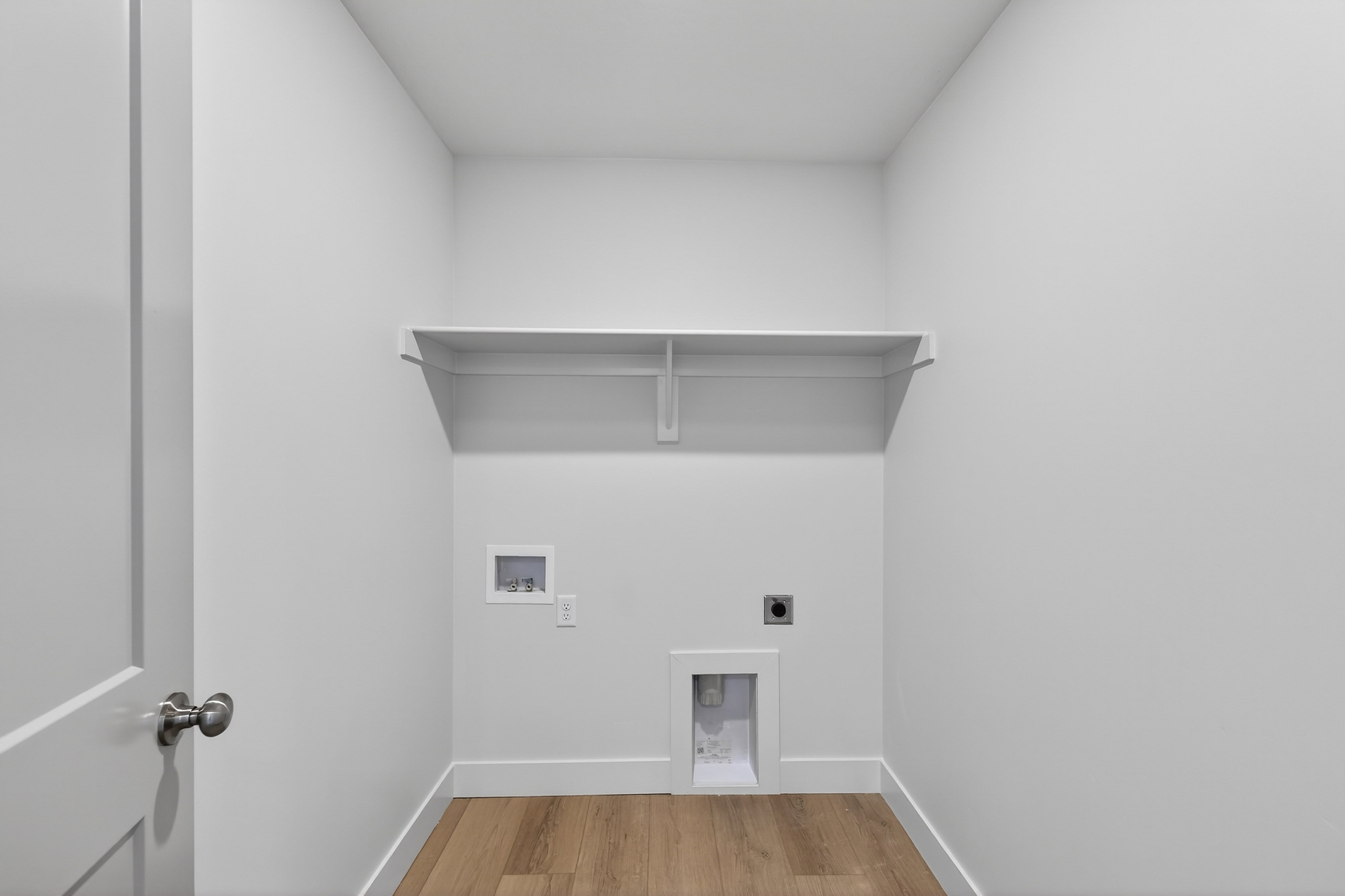 Dedicated laundry area featuring a wall-mounted shelf, utility hookups, and wood-finish flooring