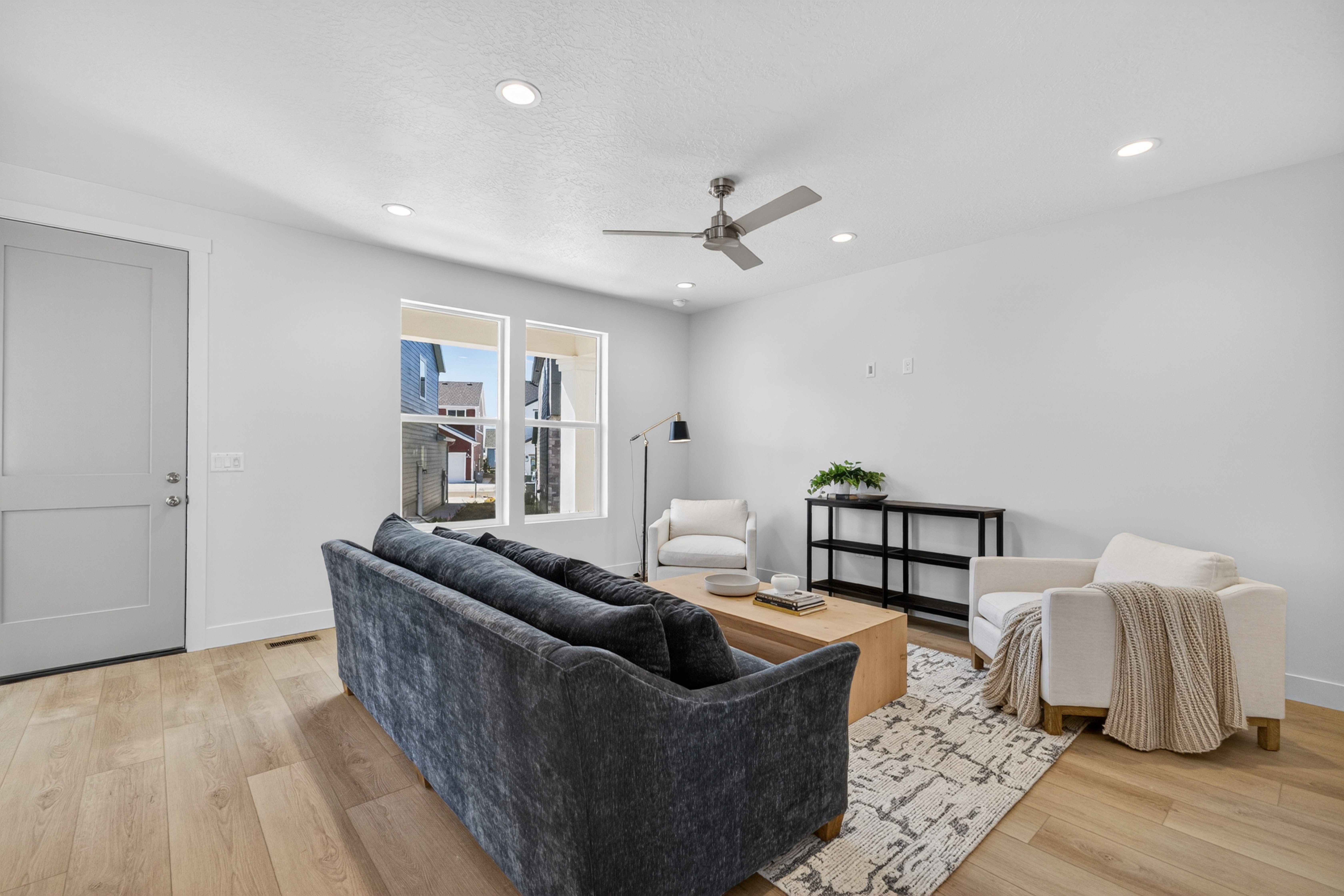 Spacious living area featuring light wood-finish flooring, recessed lighting, and a contemporary ceiling fan