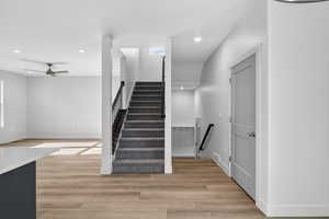 Staircase with wood finished floors, a ceiling fan, and recessed lighting