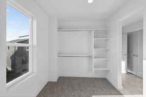 Walk in closet featuring light carpet and light marble finish floors