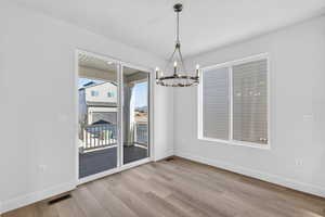 Unfurnished dining area with light wood-style floors and suspended lighting