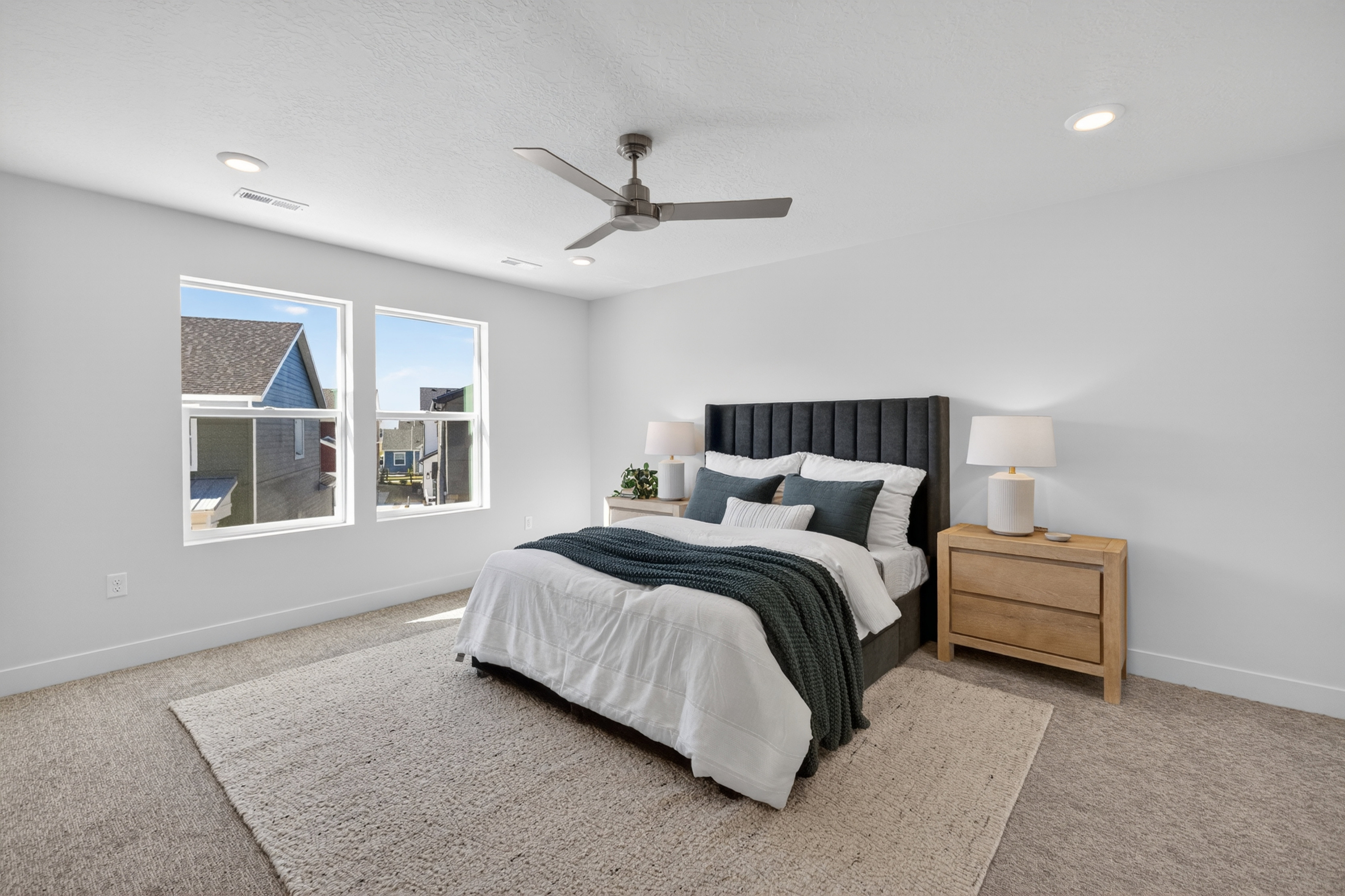 Spacious bedroom featuring light neutral walls, two large windows, recessed lighting, and a contemporary ceiling fan
