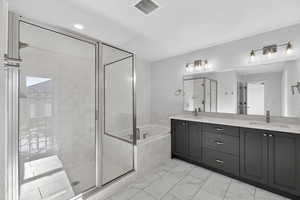 Bathroom with a stall shower, a bath, double vanity, and recessed lighting