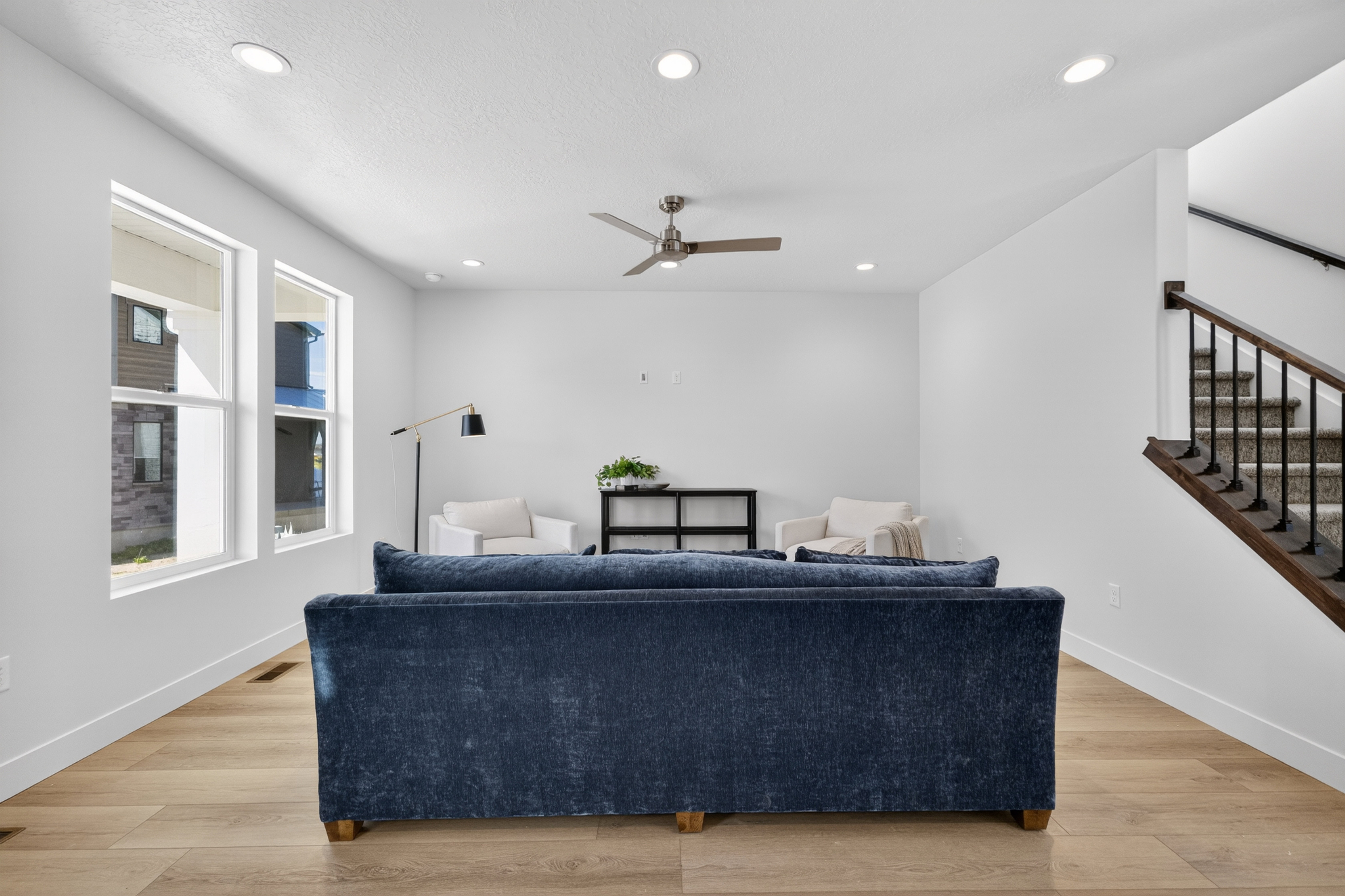 Spacious living area featuring light wood-finish flooring, white walls, and recessed lighting